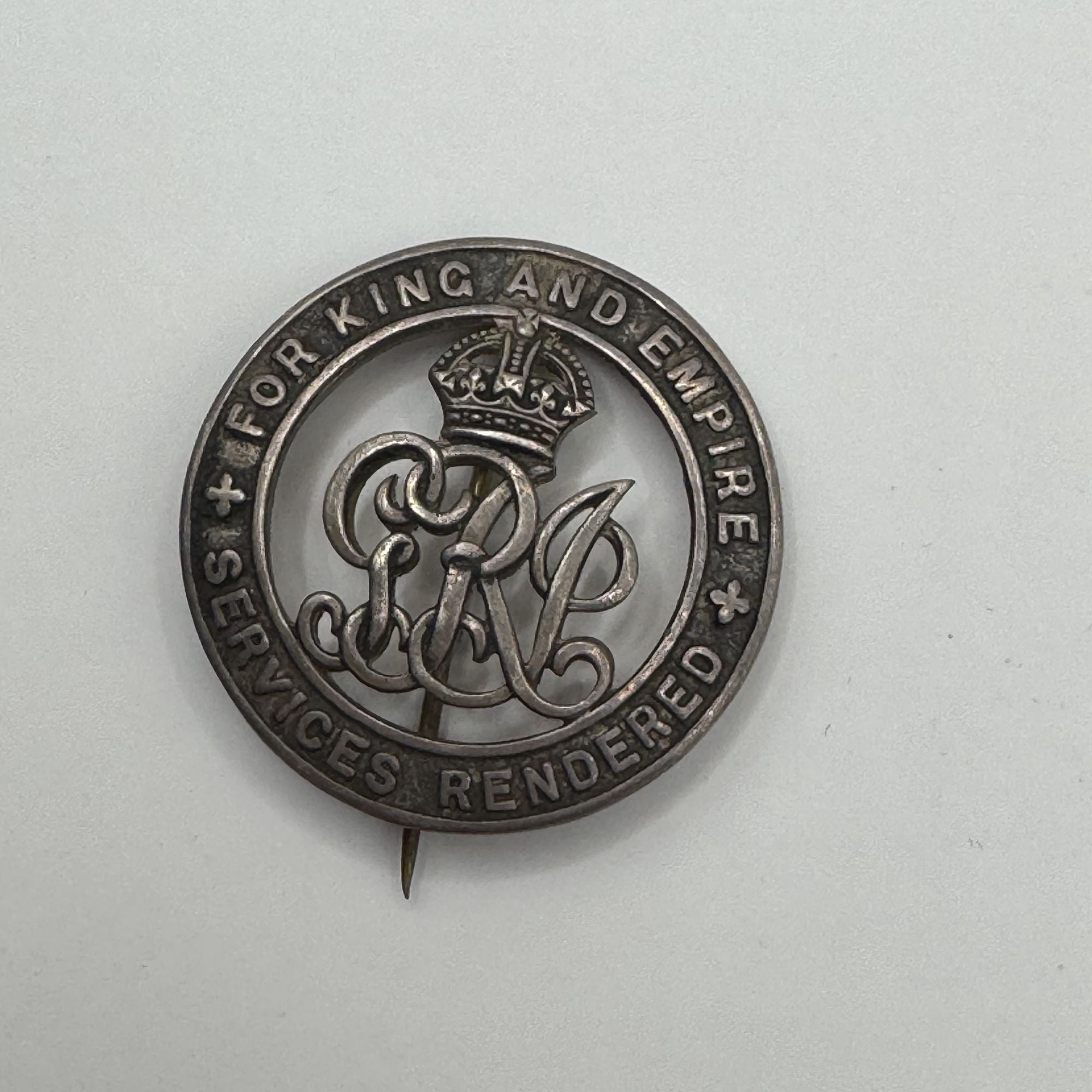 Silver badge with text 'For King and Empire' on a light gray background