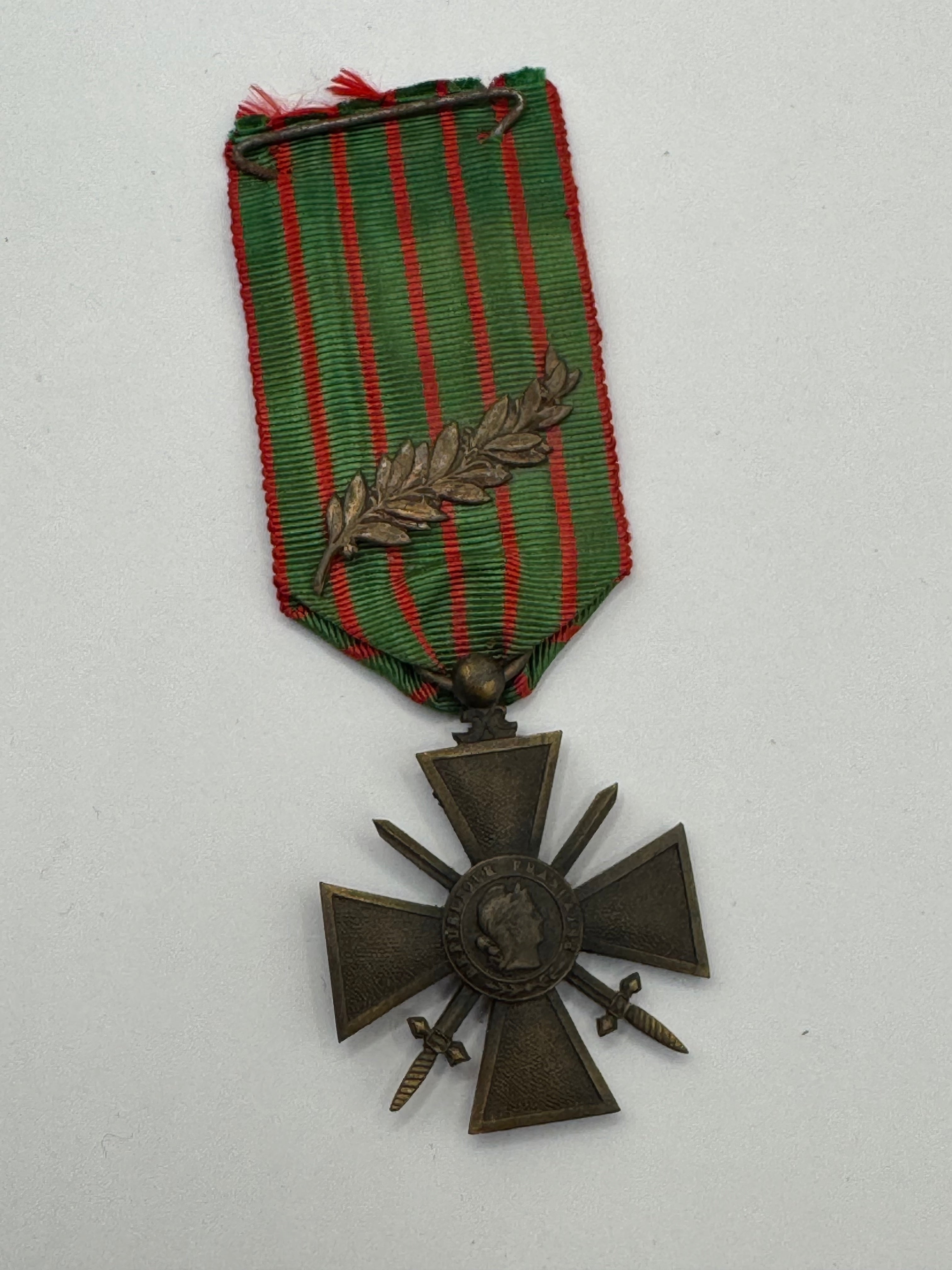 Bronze military cross with green and red ribbon on a white background