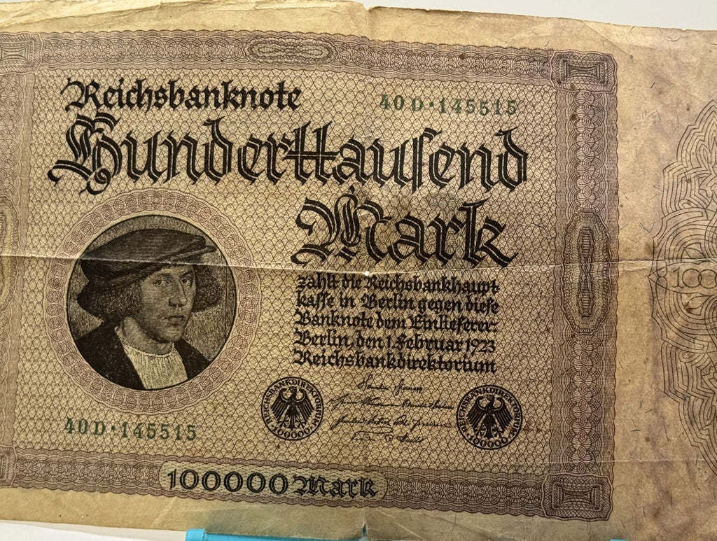 Vintage German banknote with a portrait and text, next to a blue pen for scale.