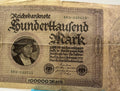 Vintage German banknote with a portrait and text, next to a blue pen for scale.
