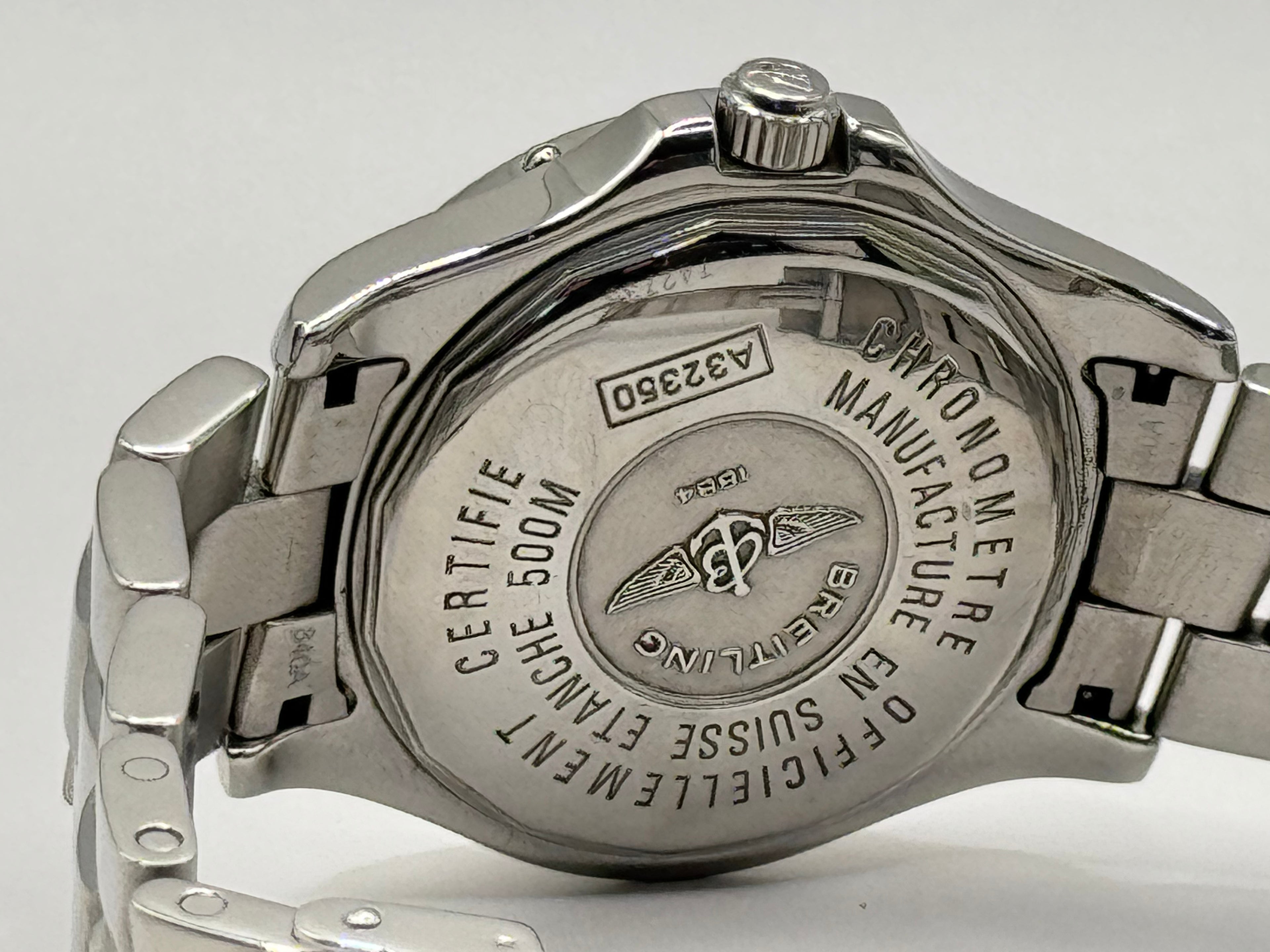 Close-up of a silver watch with brand engraving on a white background