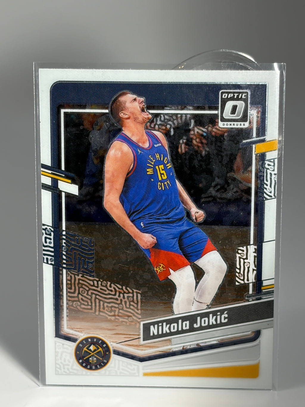 Basketball trading card of a player in action, encased in clear plastic on a gray background