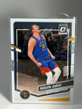 Basketball trading card of a player in action, encased in clear plastic on a gray background