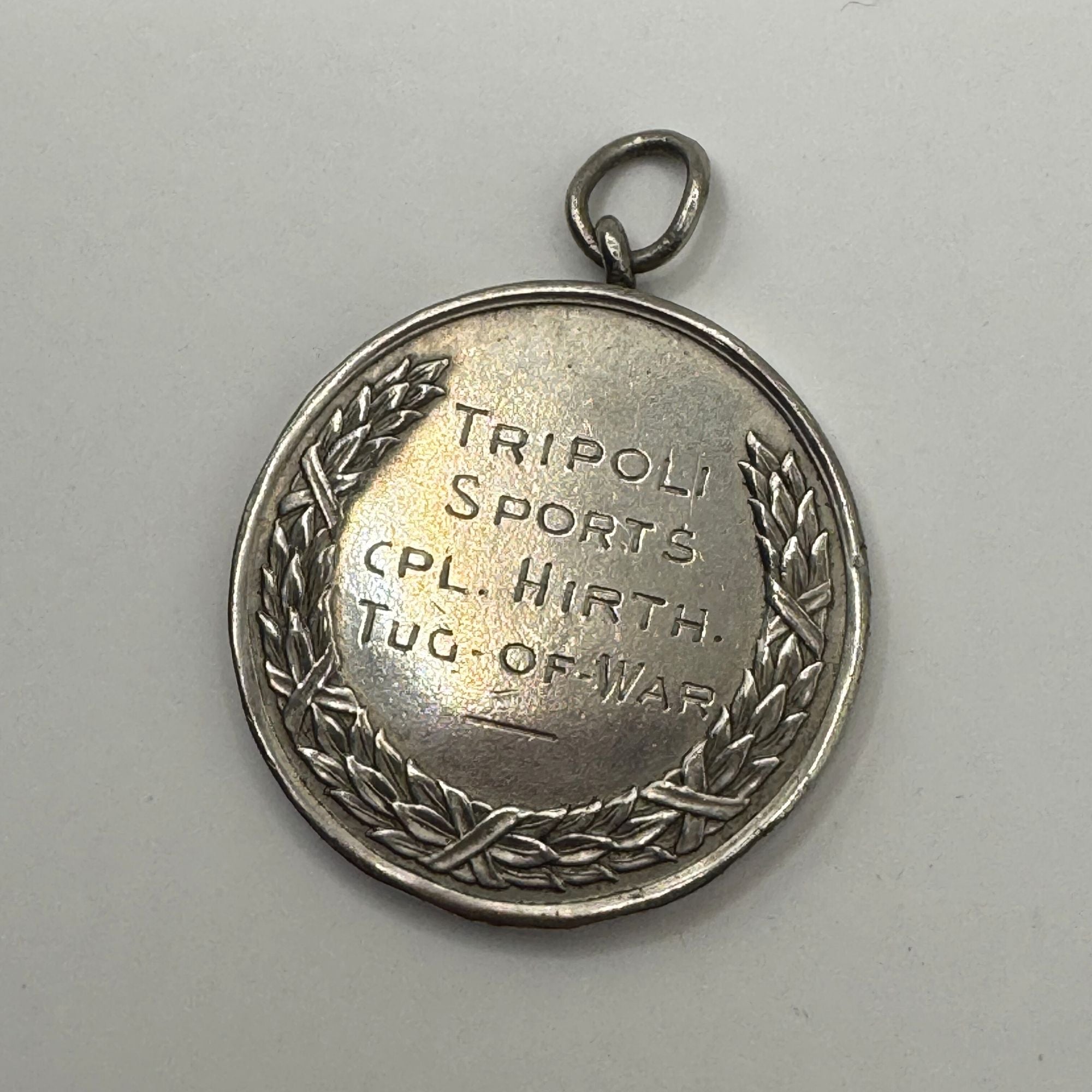 Silver medal with engraved text on a gray background