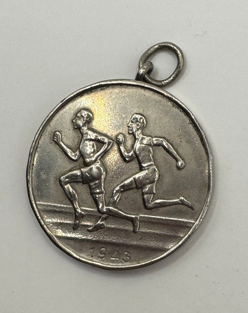 Silver medal with runners and the year 1946 on a gray background
