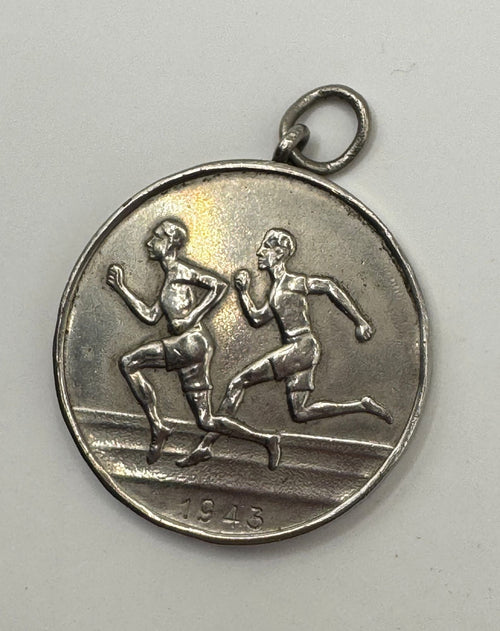 Silver medal with runners and the year 1946 on a gray background