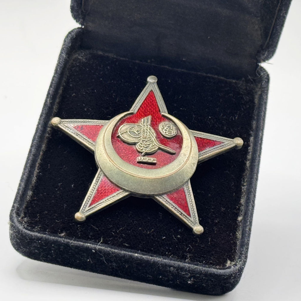 Star-shaped badge with a crescent moon and Arabic text in a black velvet box