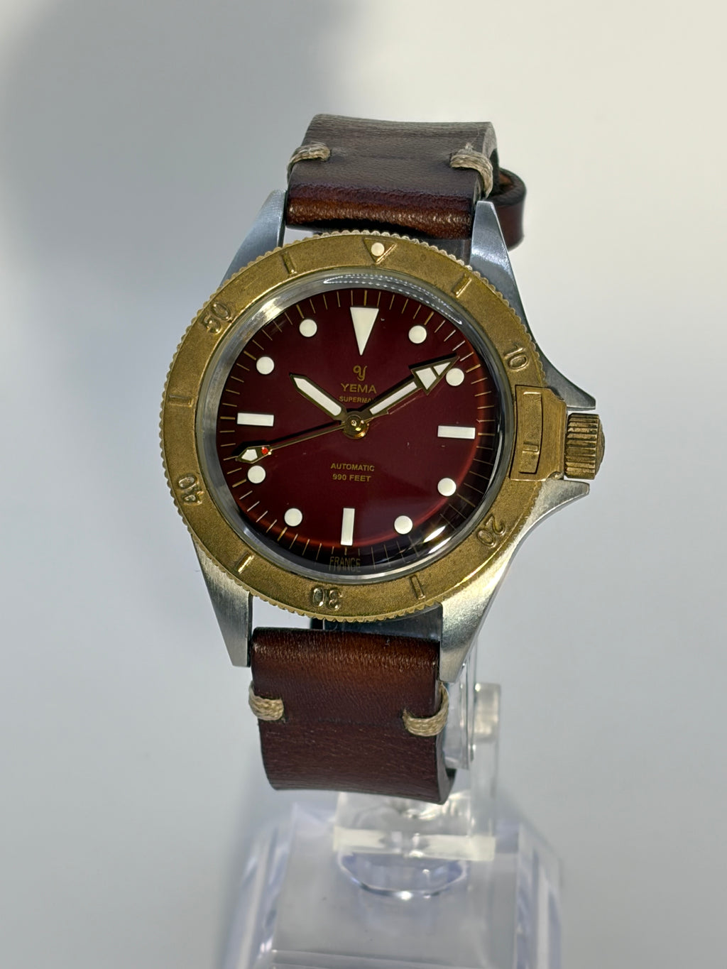Wristwatch with brown leather strap and red face on a white background