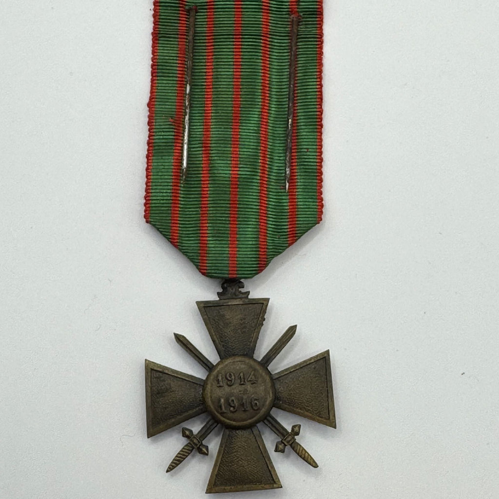 Bronze military cross with green and red ribbon on a white background