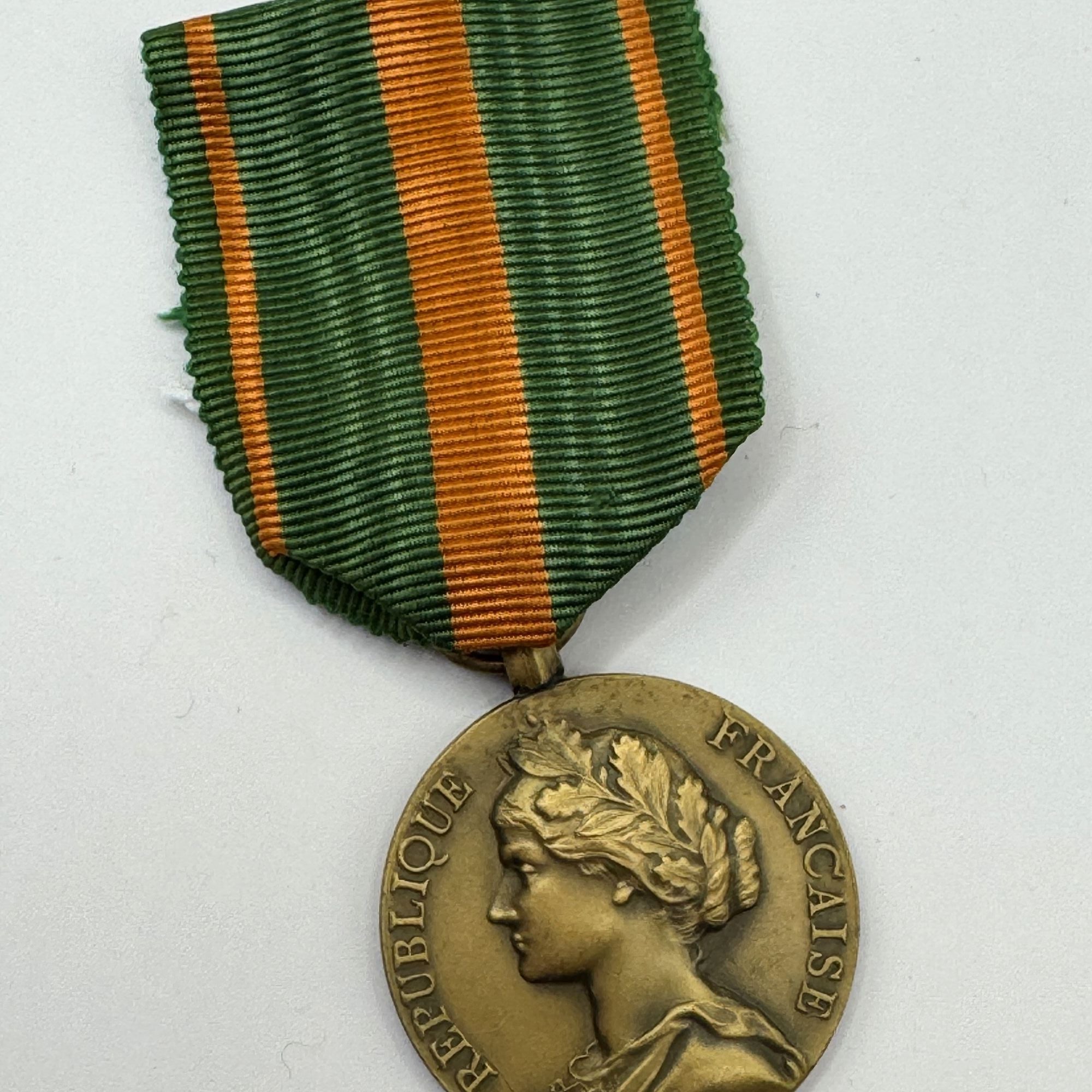 Bronze medal with green and orange ribbon on a white background